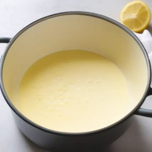 This image shows the process of mixing crushed pineapple, sugar, cornstarch, milk and lemon juice in a saucepan for making the pineapple cake filling.